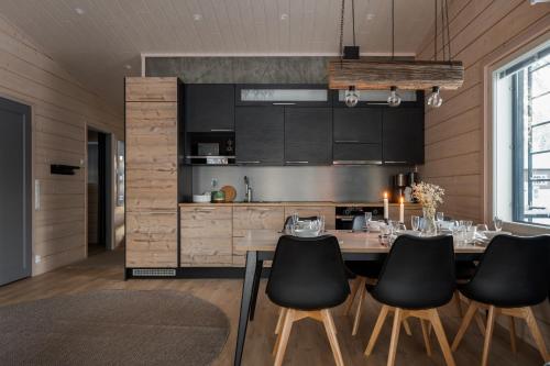 a kitchen with a table and black chairs at Louhi B in Äkäslompolo
