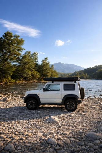 Ein weißer Jeep parkte auf den Felsen in der Nähe eines Flusses. in der Unterkunft Discovery Compass in Tirana