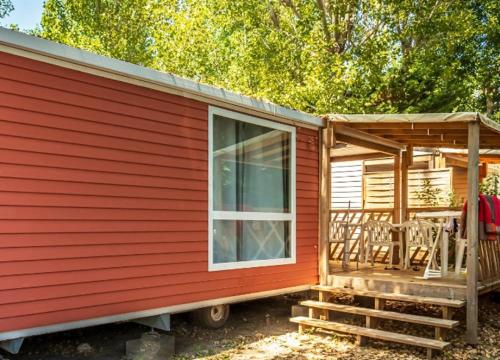 a red tiny house with a porch and a window at ZEcamping 4 étoiles 500m plage piscine couverte animaux acceptés club enfant in Sérignan