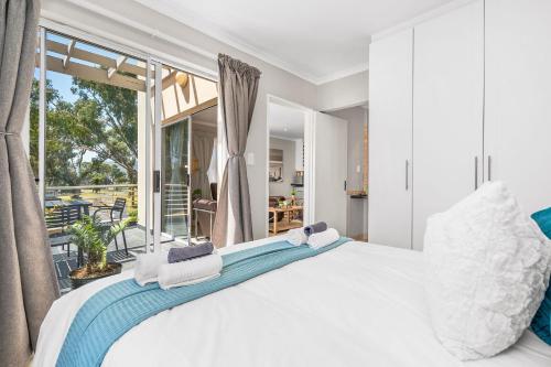 a bedroom with a large white bed and a balcony at Coral Grove in Strand