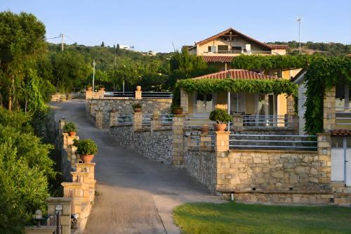 a house with a stone wall and a road at Alexandros Beachfront Apartments near Petalidi with Private Sunbeds & Sea View in Kalamaki Messinia