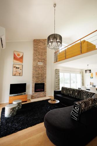 a living room with a black couch and a fireplace at Home In Green Caldera in Furnas