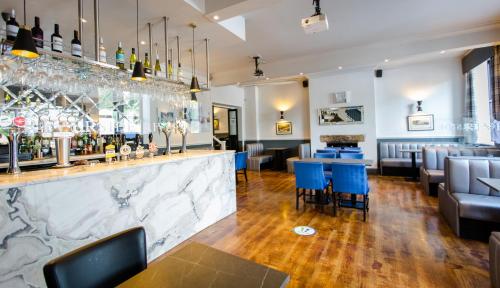 a restaurant with a bar with blue chairs and tables at Ilkley Riverside Hotel in Ilkley