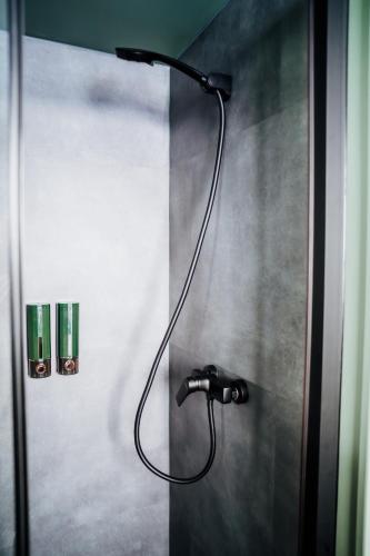 a shower with a black shower head on a wall at TogetherNest - Cedar in Mătişeşti