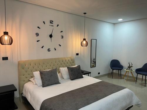 a bedroom with a large bed with a clock on the wall at Hotel Merlott 70 in Medellín