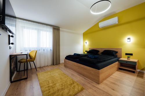 a bedroom with a bed with a yellow wall at KNB City Suites in Odorheiu Secuiesc