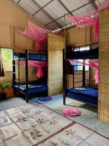 a room with three bunk beds with pink sheets at Sea PoeTree in Koh Rong Sanloem