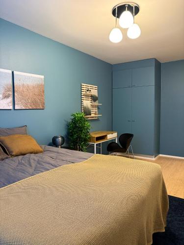 a bedroom with blue walls and a bed and a desk at Tilava ja elegantti kolmio in Kokkola