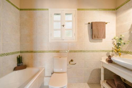 a bathroom with a toilet and a tub and a sink at Nikolas by Vintage Travel in Fiskardo