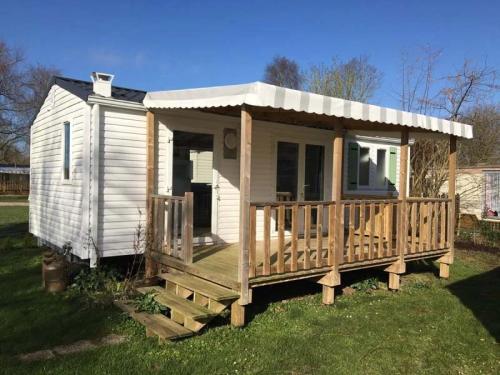 a small white house with a wooden porch at ZEcamping 4 étoiles piscine couverte piscine chauffée locatif 4 pers in Wavans