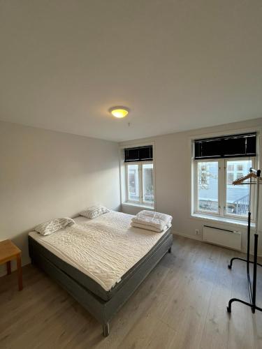 a bedroom with a bed and two windows at Nobelgården in Harstad