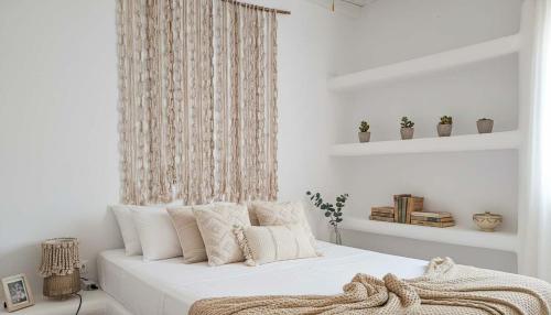 a white bedroom with a bed with white sheets and pillows at Stunning Sea-View Villa w Access to Shared Pools in Mikonos