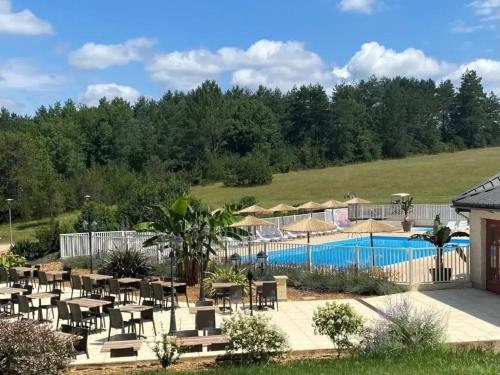 a resort with a pool and tables and chairs at ZEcamping 3 étoiles animaux acceptés tennis piscine et soirées animées in Pézuls