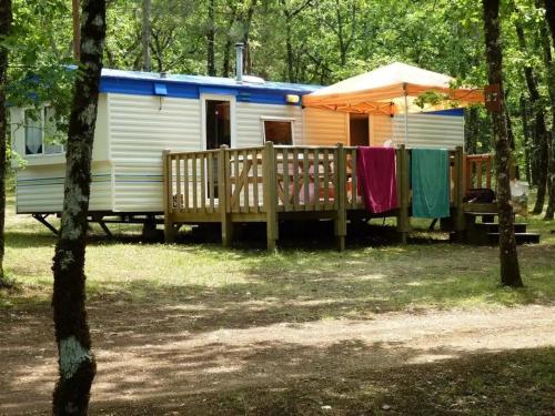 a blue and white caravan in the woods with a wooden fence at ZEcamping 3 étoiles animaux acceptés tennis piscine et soirées animées in Pézuls