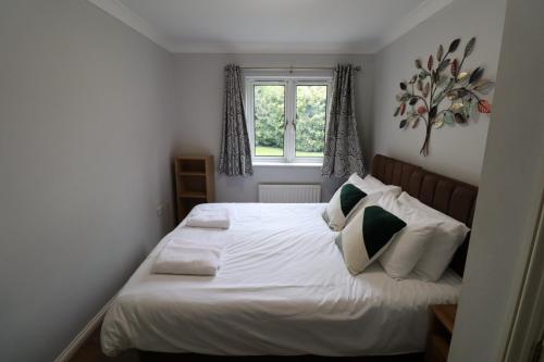 a bedroom with a bed with white sheets and pillows at Bracknell Spacious 2 Bedroom Apartment in Bracknell
