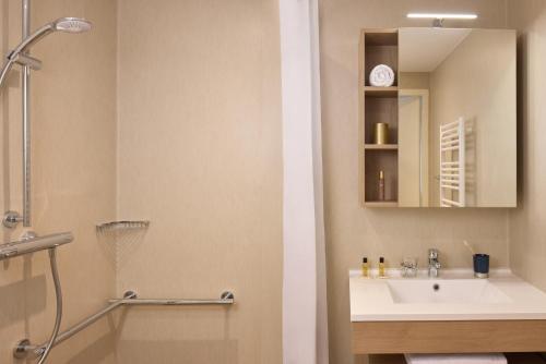 a bathroom with a shower and a sink and a mirror at Quality Aparthotel Voiron in Voiron