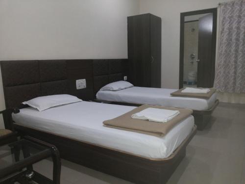 2 Einzelbetten in einem Zimmer mit Spiegel in der Unterkunft Hotel Saket Heritage in Raigarh