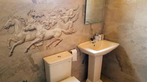 a bathroom with a sink and a wall with horses on it at The Nature in Tangalle