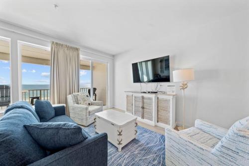 a living room with a blue couch and a tv at Sea Glass 404 by Youngs Suncoast in Gulf Shores