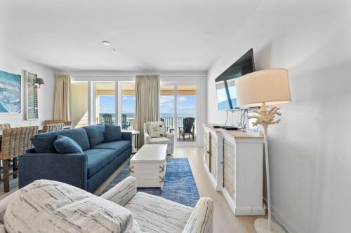 a living room with a blue couch and a tv at Sea Glass 404 by Youngs Suncoast in Gulf Shores