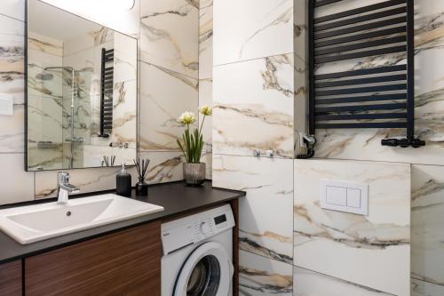 a bathroom with a sink and a washing machine at Słoneczne Polany by Apart Concept Podhale in Kościelisko