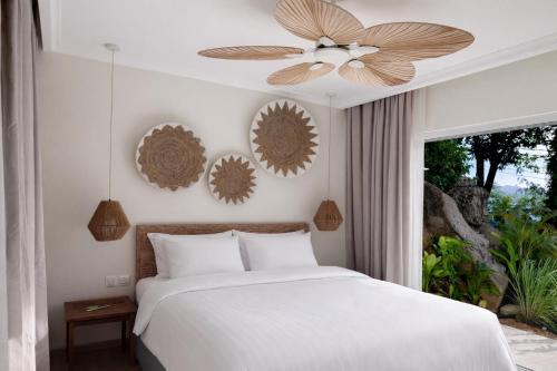 a bedroom with a white bed and a ceiling fan at Cocoon Self-Catering Apartments in Anse a La Mouche