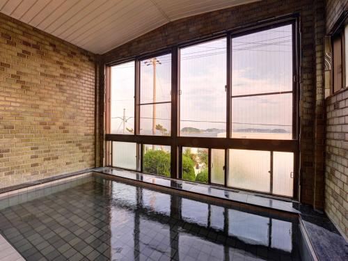 an empty room with a pool and windows at Takumi Kanko Hotel in Minamichita