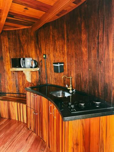 a kitchen with a sink and a wooden wall at Pousada tanoeiro cabana Carvalho in Monte Belo