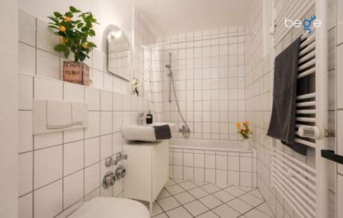 a white tiled bathroom with a toilet and a tub at BEGE APARTMENTS LoftWork in Lüdenscheid
