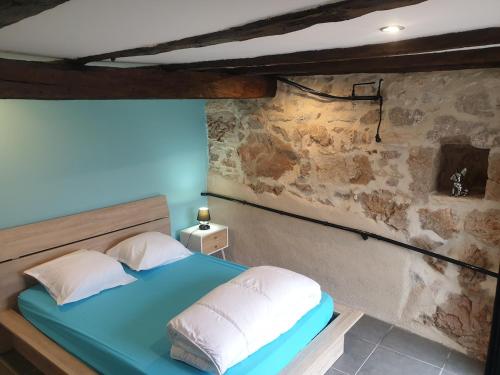 a bedroom with a blue bed and a stone wall at Coeur de Koss Climatisé in Blars