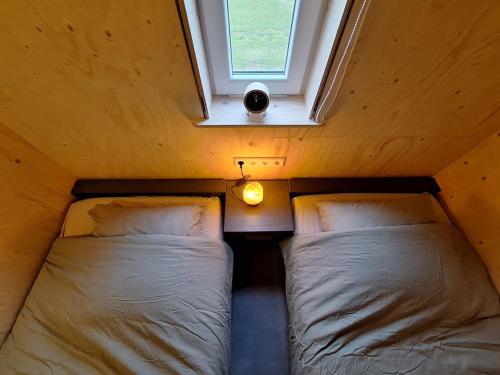 two beds in a small room with a window at Zee aan Geluk in Sint Maartensvlotbrug