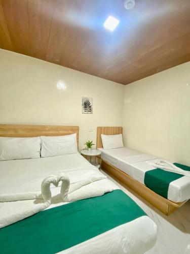 two beds in a small room with green and white at RedDoorz at Urban Hotel in Zamboanga