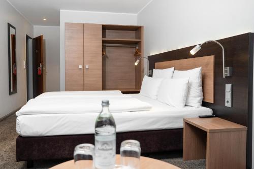 a hotel room with a bed with a bottle on a table at Astor & Aparthotel in Cologne