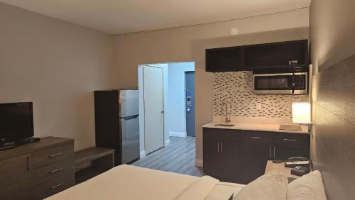 a room with a kitchen with a bed and a microwave at Motel 6 Sault Ste. Marie, ON in Sault Ste. Marie