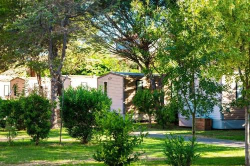 a house in a yard with trees and grass at ZEcamping 4 familial piscine chauffée club enfant animations au calme in Canet-en-Roussillon