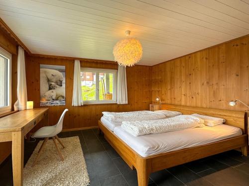 a bedroom with a bed and a desk and a chandelier at Chalet apartment with Mountain View in Bettmeralp