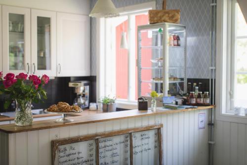 a kitchen with white cabinets and a counter with pink flowers at Sävö Vandrarhem & Café in Västerljung
