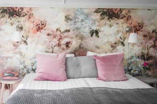 a bedroom with a bed with pink pillows and a floral wall at Sävö Vandrarhem & Café in Västerljung