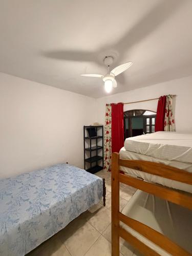 a bedroom with a bed and a ceiling fan at Casa de Praia Bertioga-Costa do Sol Guaratuba in Bertioga