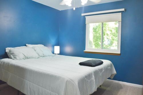 a blue bedroom with a large bed with a window at Exclusive 2B1B Prime Location in Sylvan Lake