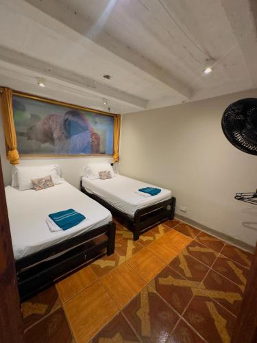 two beds in a room with a painting on the wall at AMAZONAS EXPLORERS LETICIA in Leticia