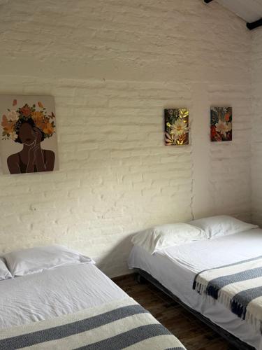 a bedroom with two beds and two paintings on the wall at ecopolis birds lodge in El Queremal
