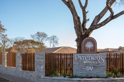 a sign in front of a fence with a tree at PYRENÉUS RESIDENCE GAV Resorts in Pirenópolis