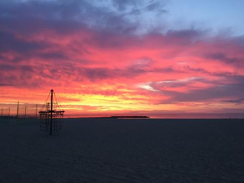 a sunset over the ocean with a tower in the water at Brasilia Hôtel in Palavas-les-Flots