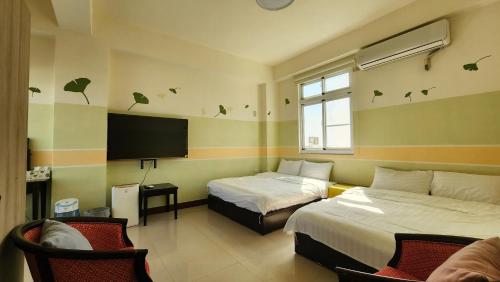 a hotel room with two beds and a flat screen tv at Dongle B&B in Taitung City