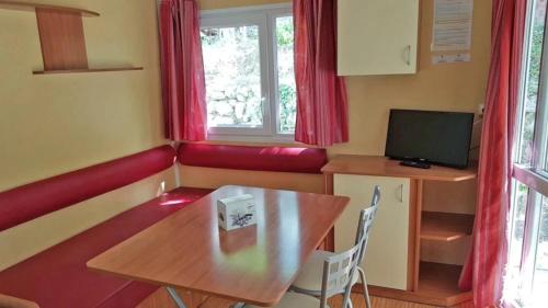 a small room with a table and a television at ZEcamping 3 étoiles animations à 2 km du lac de Sainte Croix in Moustiers-Sainte-Marie
