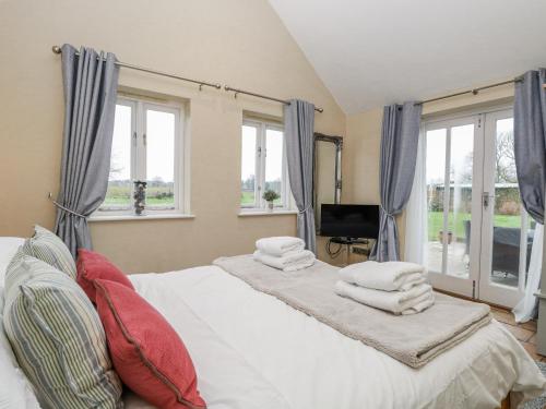 a bedroom with two beds with pillows and windows at Ivy Barn in Norwich