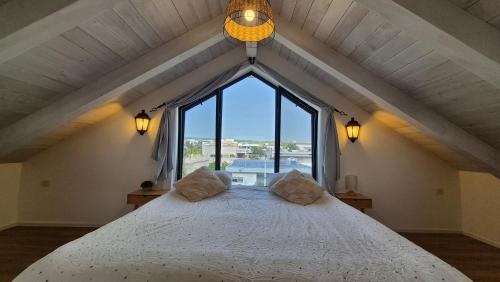 a bedroom with a large bed with a large window at קיבוץ שדה נחום Green House in Sede Naẖum