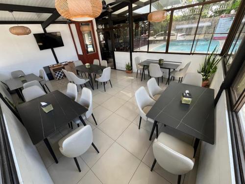 a restaurant with black tables and white chairs at Hotel Wilson Anexo in Liberia