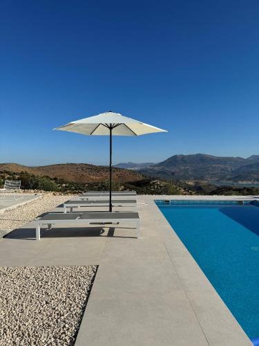 a white umbrella sitting next to a swimming pool at Casa Horizonte in Iznájar